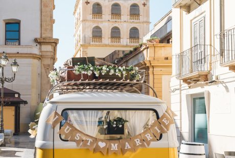 Van vintage jaune avec une pancarte Just Married devant un village pittoresque
