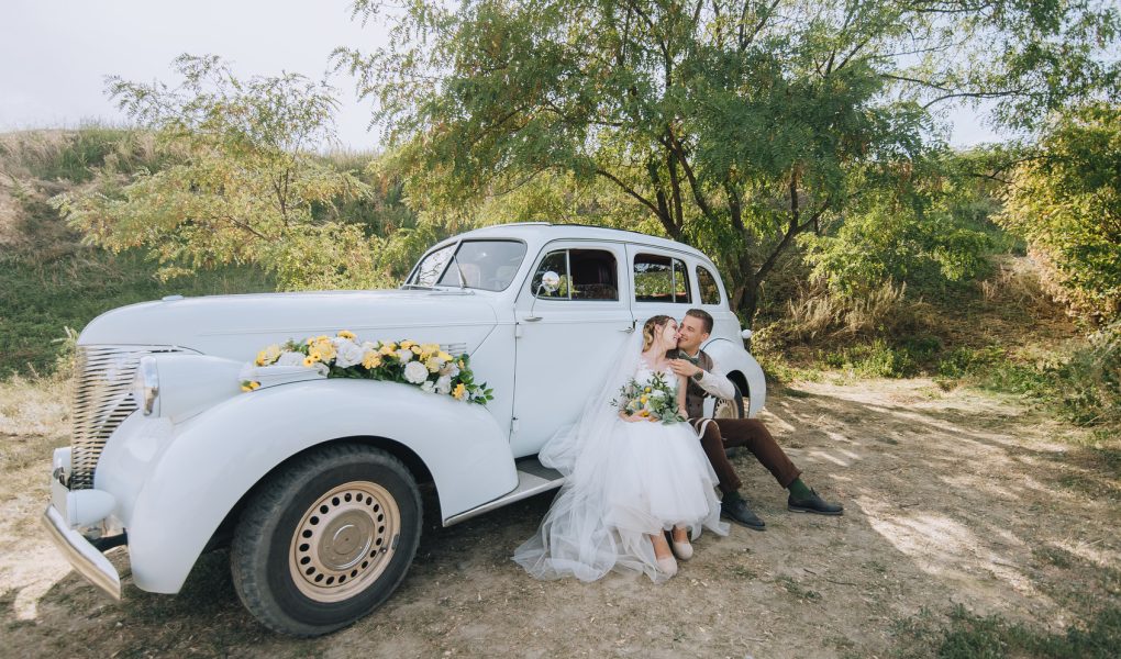 Mariés enlacés près d'une voiture classique le jour du mariage